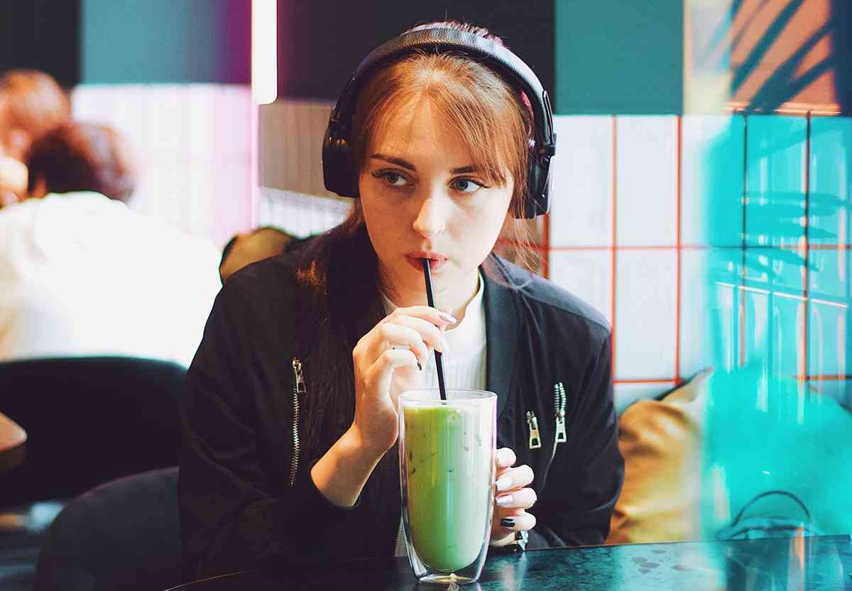 Woman on the autism spectrum wearing noise-canceling headphones in a coffee shop.