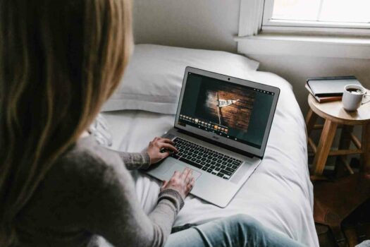 Woman with a disability or chronic illness sitting in bed filling out college applications.