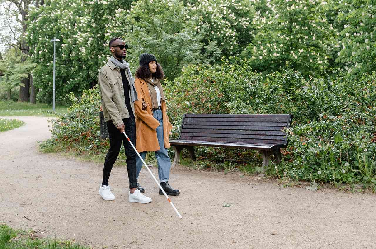 Vision loss and blindness coping guide: Blind man with assistant learning to use a white cane.