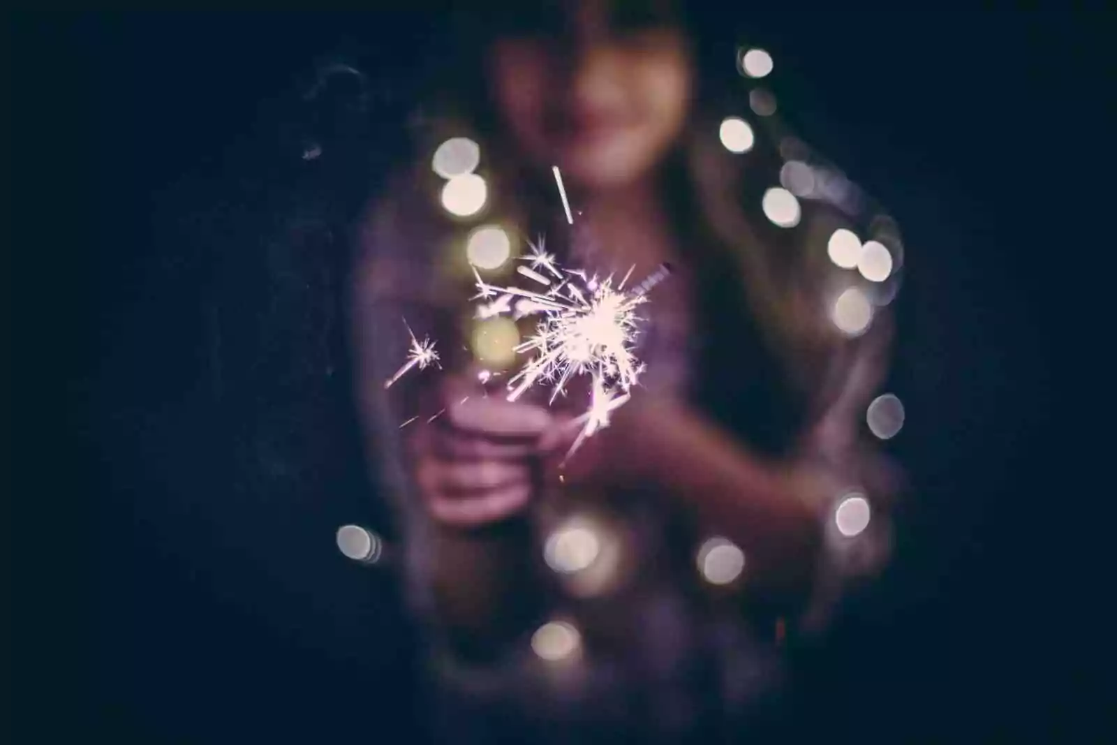 Finding hope o n dark days with mental illness. Woman holding a sparkler on a dark night.
