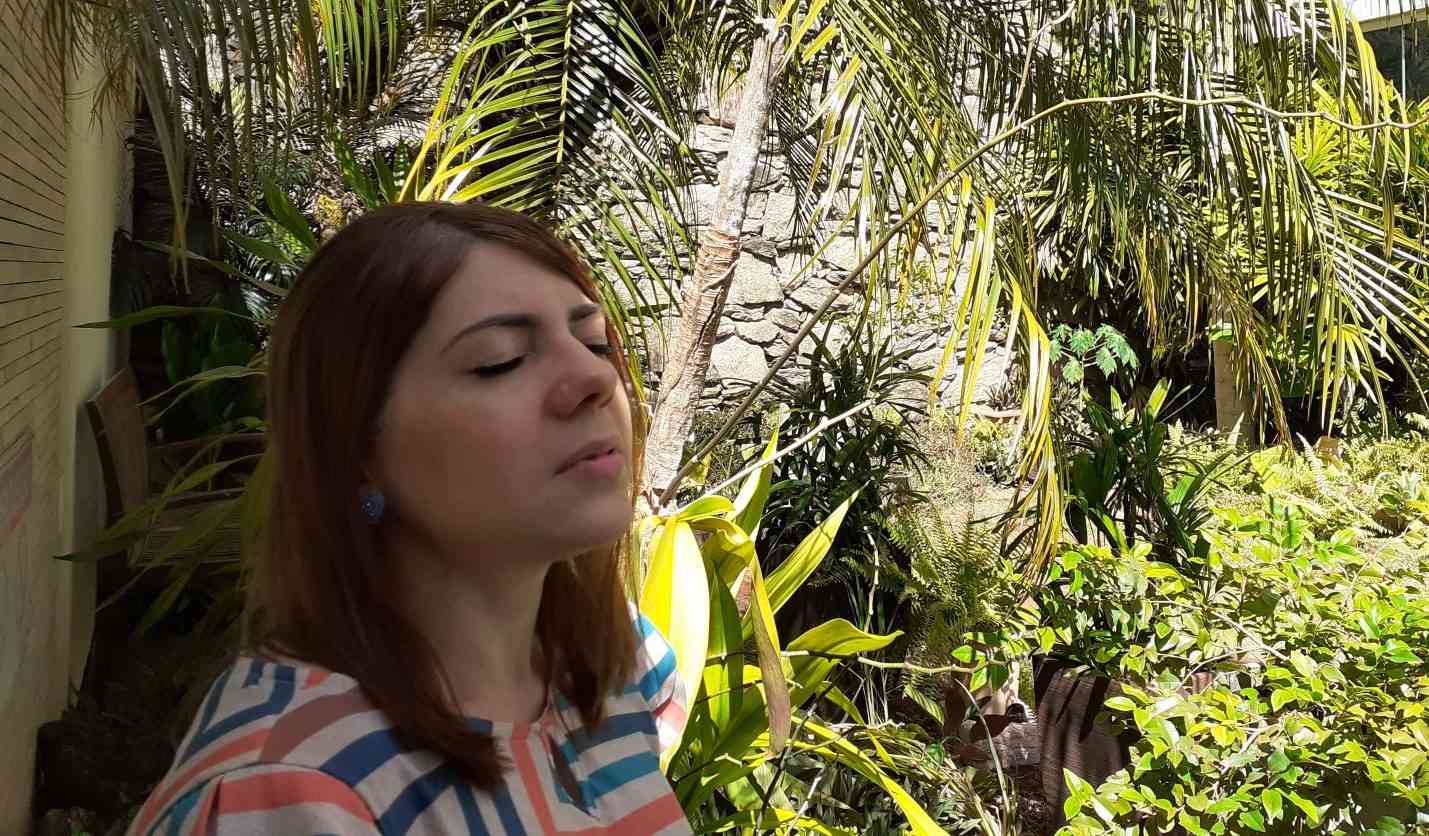 Using dialectical behavioral therapy to treat suicidal ideation and emotional dysregulation. A Caucasian woman with red hair wearing a striped shirt practices mindfulness in a tropical forest.