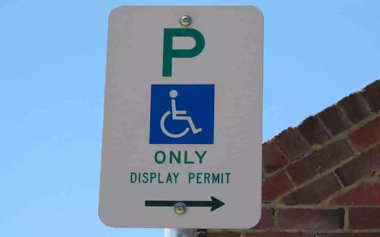 Disability parking sign. Addressing harassment when parking as someone with an invisible disability such as Parkinson's disease.