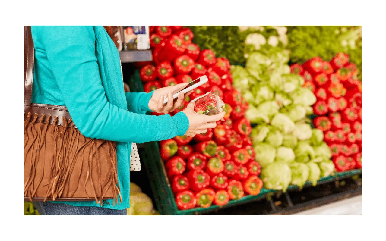 Shopping tips for blind people. A woman in the produce section of the grocery store scans a package of strawberries with a barcode app.