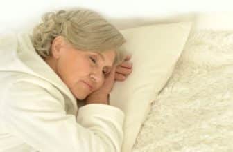 Senior woman sleeping in bed. Bedding to stop painsomnia -- insomnia caused by chronic pain.
