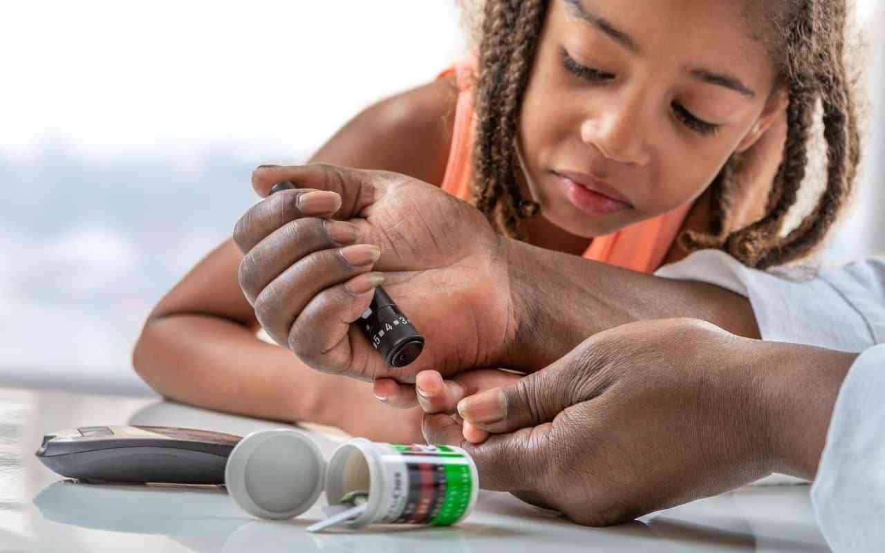 How to support a child with type 1 diabetes. Parent helping child use glucometer to check blood sugar.