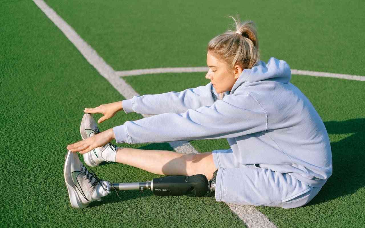 Exercises for amputees. Woman with prosthetic leg stretching.