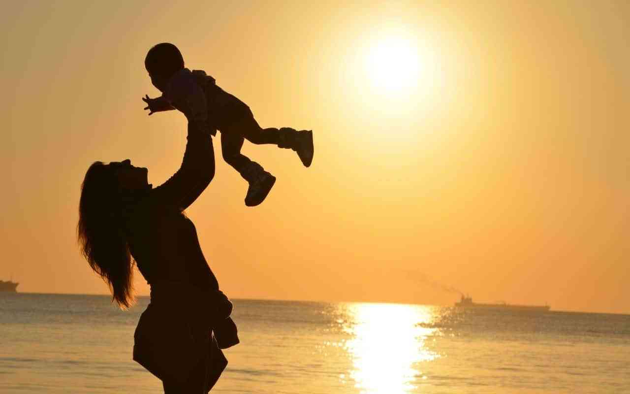 Mother holding baby at sunset.