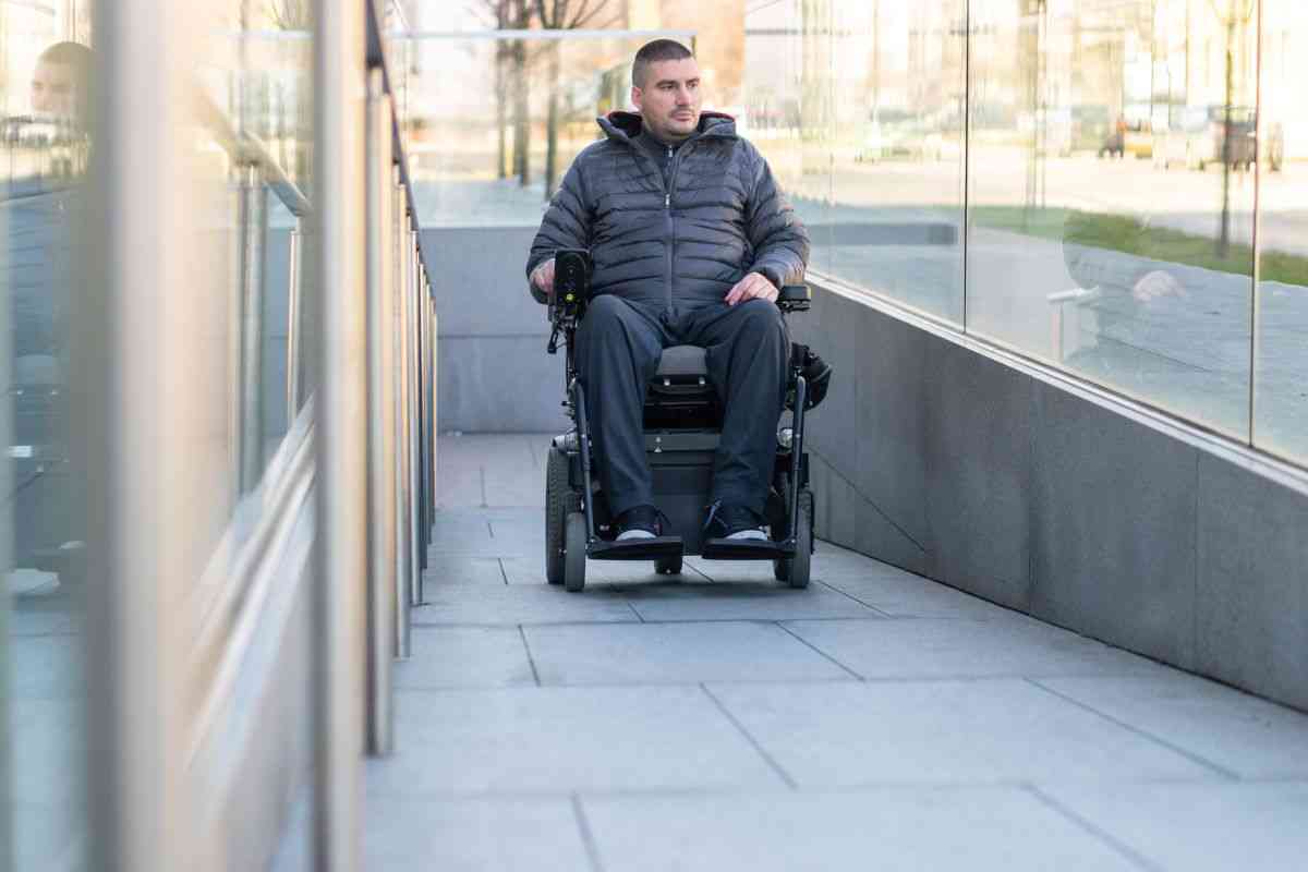 Man in power wheelchair going up ramp.