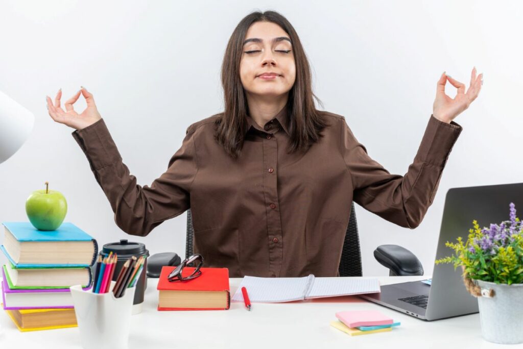 Woman meditating at desk during work or study.