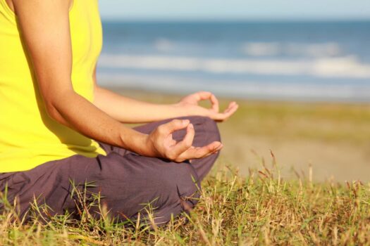 Woman in addiction recovery program meditating on the beach.