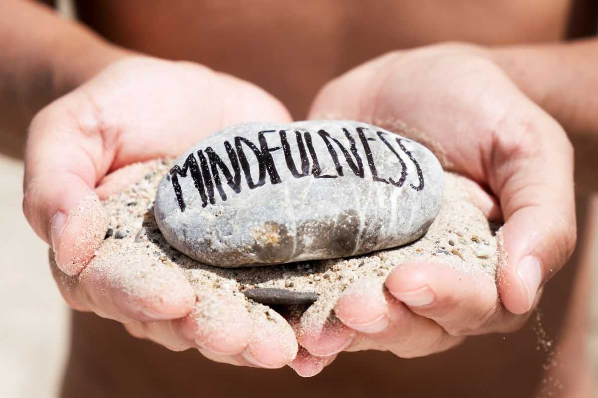 Mindfulness strategies for stress relief. Person holding a stone with the word mindfulness written on it.