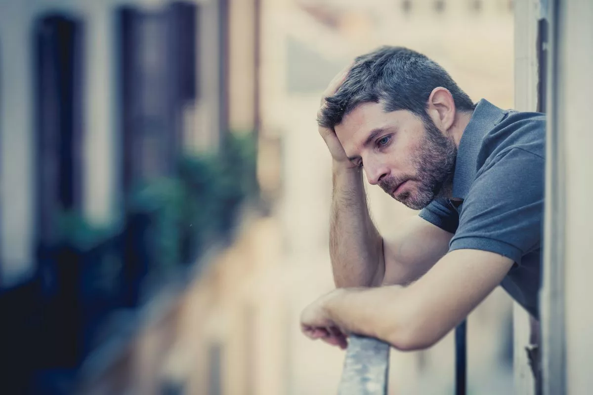 Depressed man sitting on balcony.