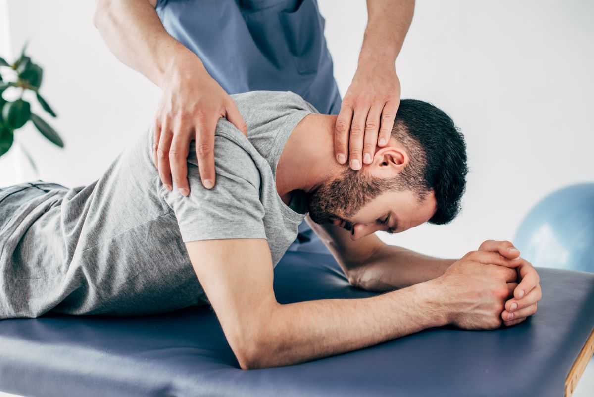 Chiropractor adjusting patient's neck and shoulder.