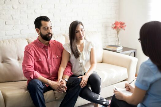 Couple in rehab meeting with a therapist for help with addiction recovery.