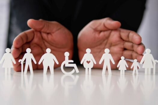 Disability inclusion: paper cutouts representing disabled people of different ages and body types including a wheelchair.