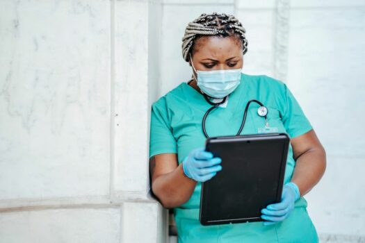 Specialized nurse consults a patient's chart on a tablet.