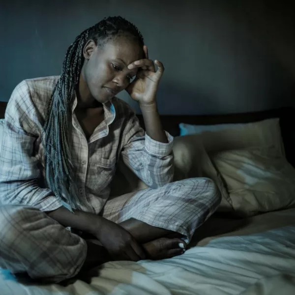 Stressed woman struggling with disability burnout sitting on her bed.