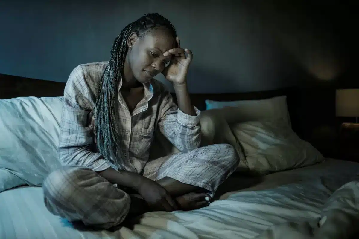 Stressed woman struggling with disability burnout sitting on her bed.