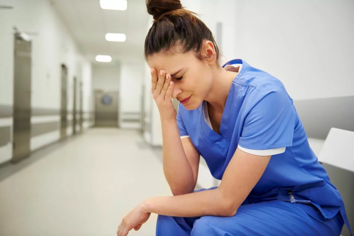 Stressed nurse resting her head in her hand.