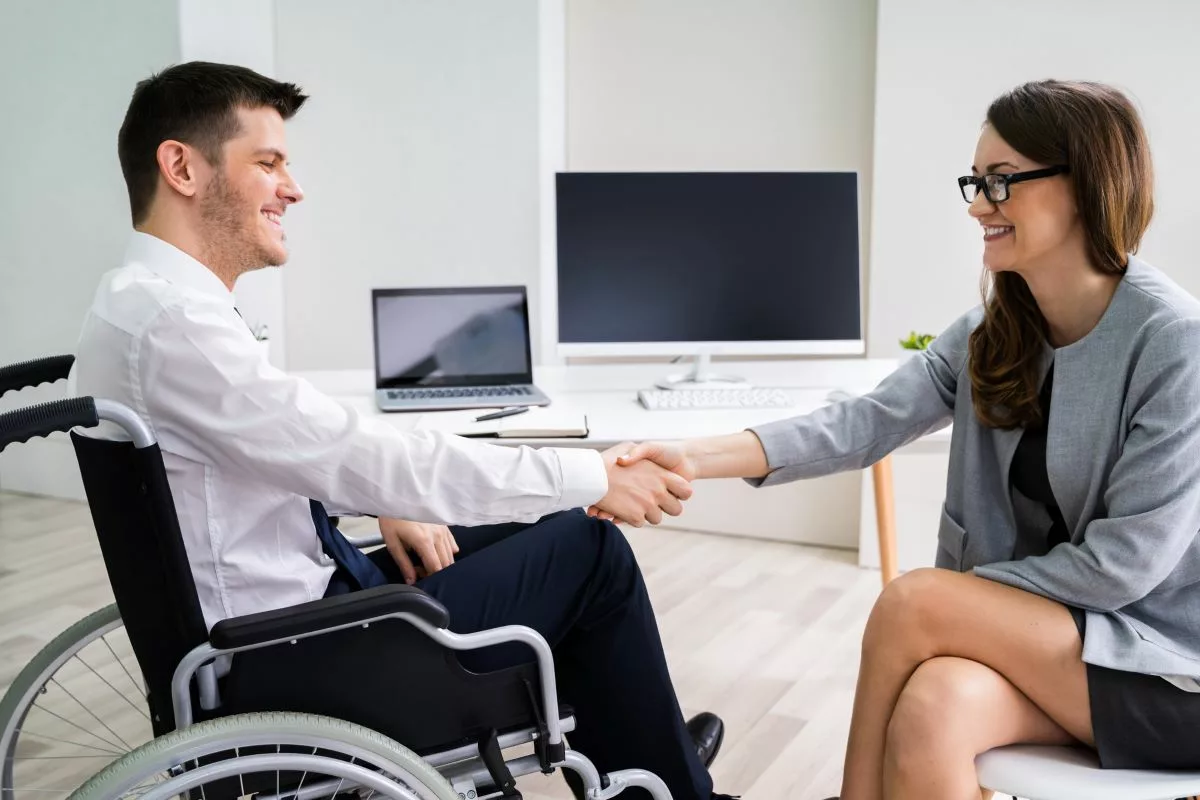 Man in wheelchair shaking hands with work colleague