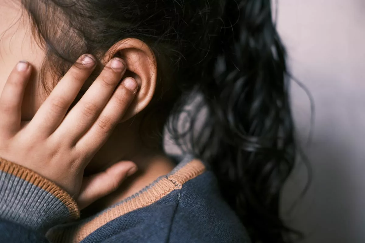 Child with microtia touching her ear.