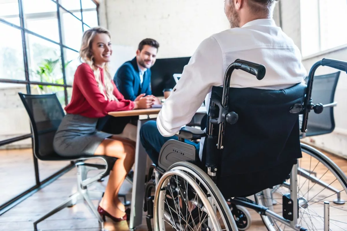 Man in wheelchair meeting with HR about disability accommodations.