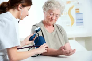 Nurse taking elderly patient's blood pressure.