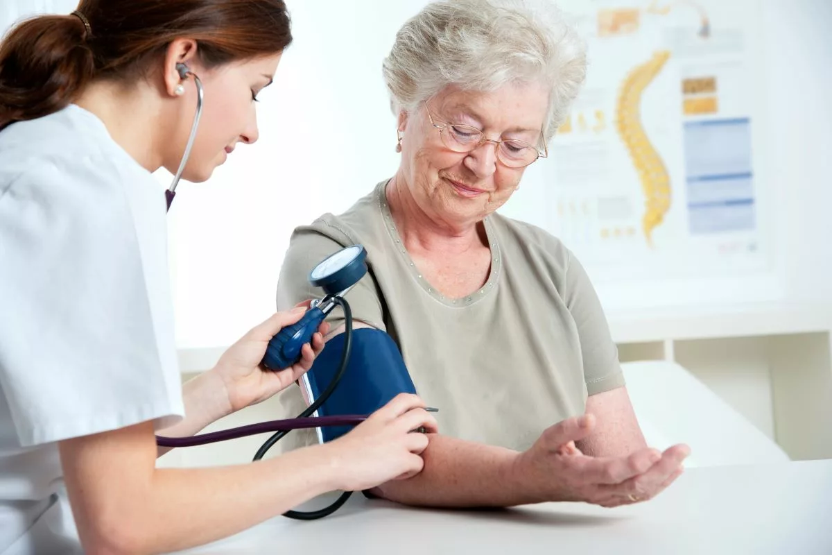 Nurse taking elderly patient's blood pressure.