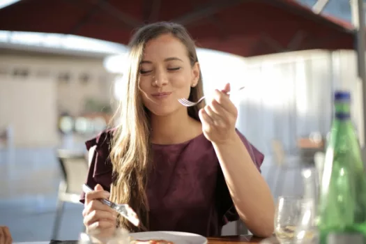 Woman eating at a cafe outdoors.