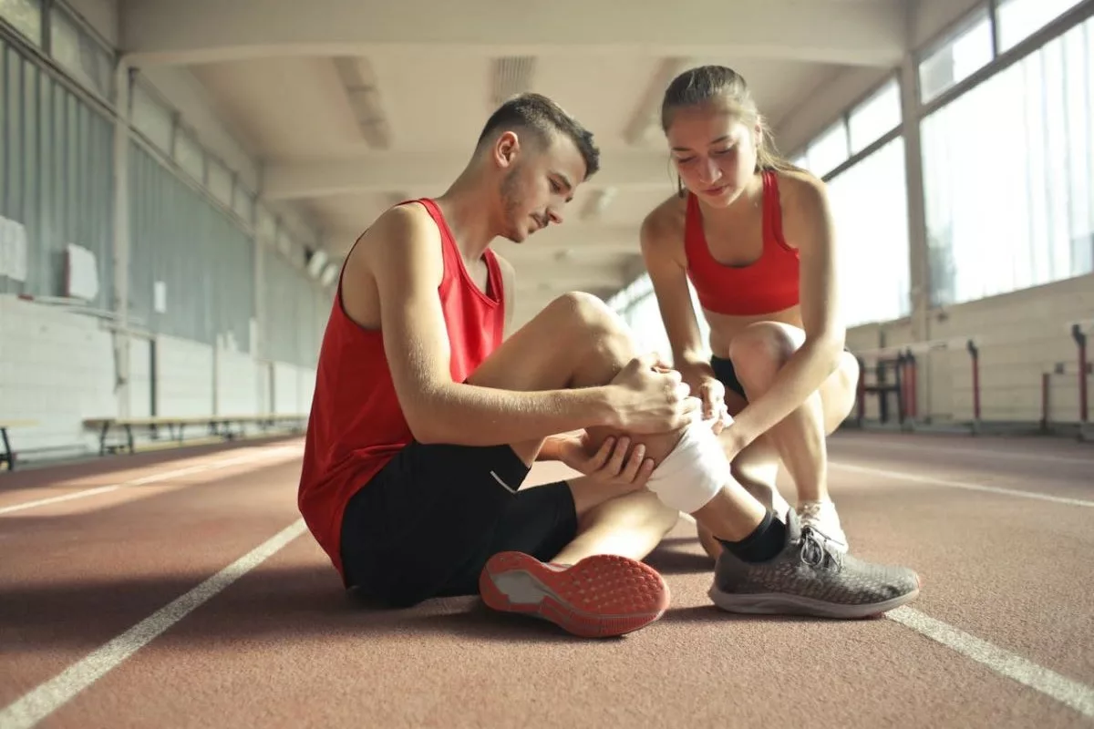 Woman wrapping man's leg due to a sports injury.