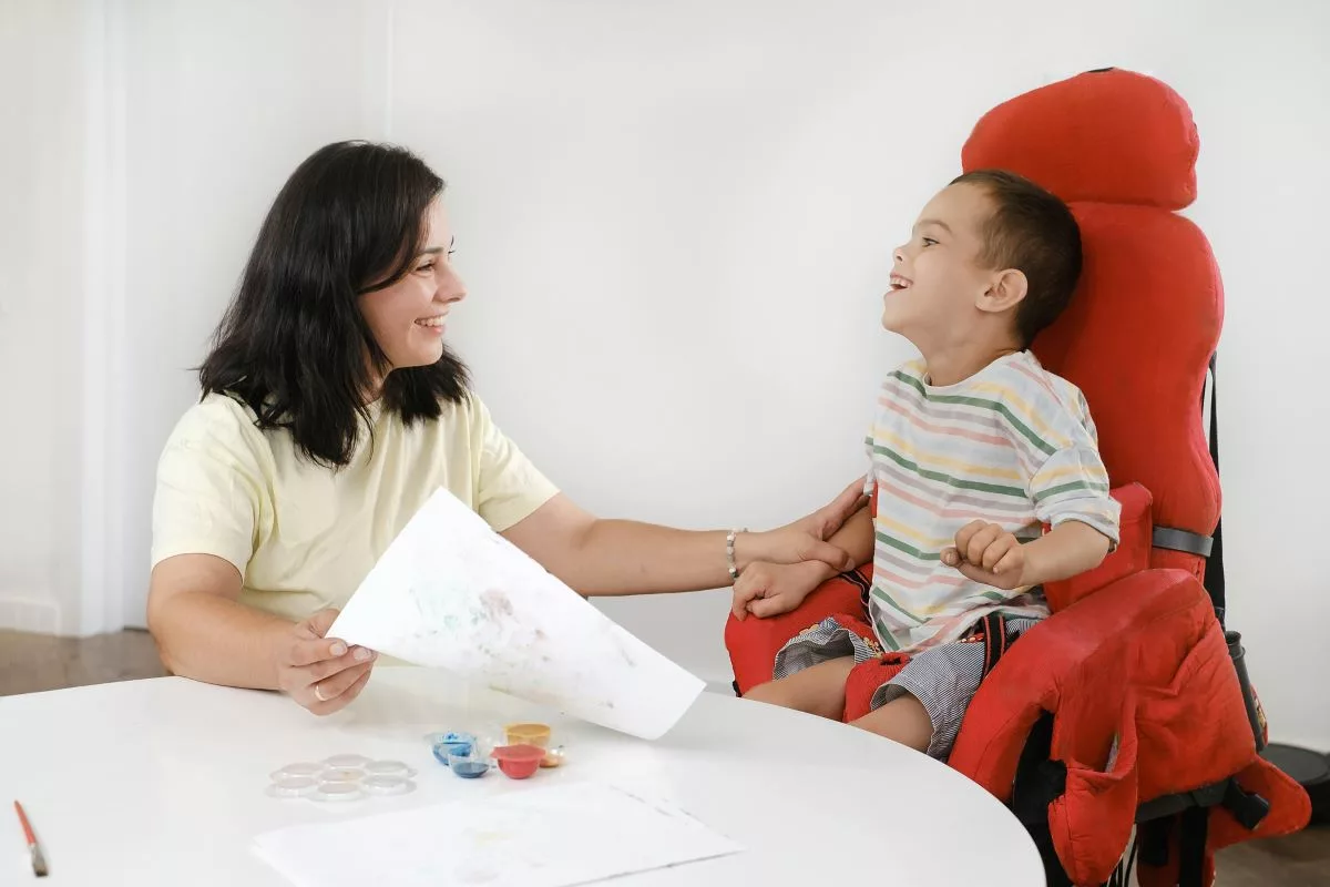 Boy with a disability laughing with his mother.