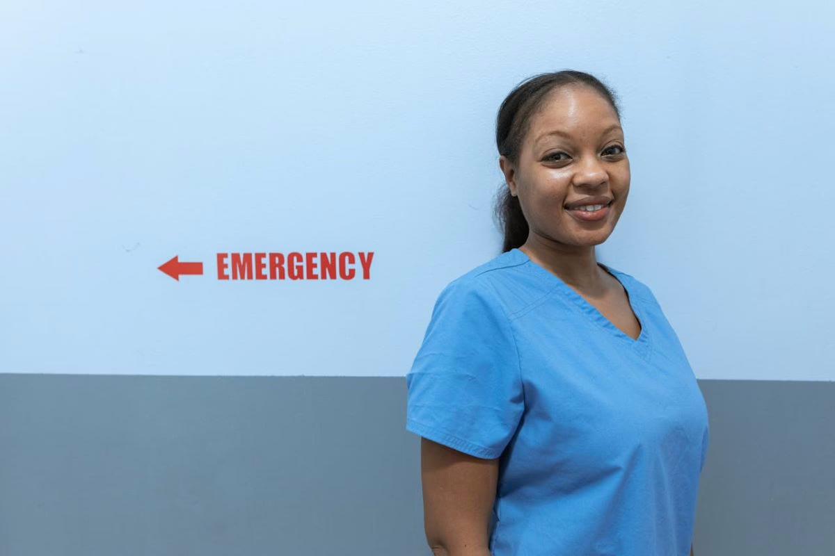 Nurse standing by emergency room sign.