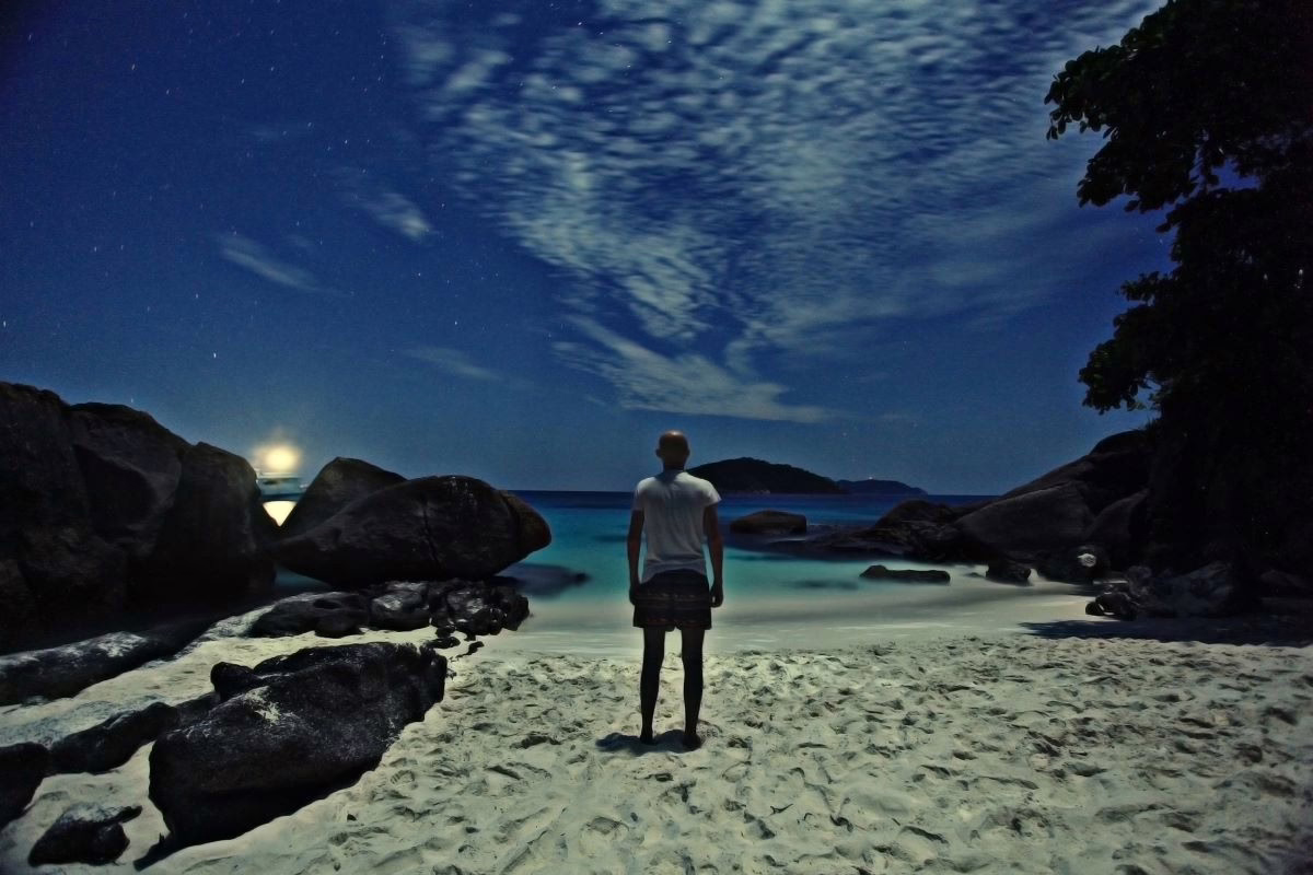 Man looking at ocean at sunset.