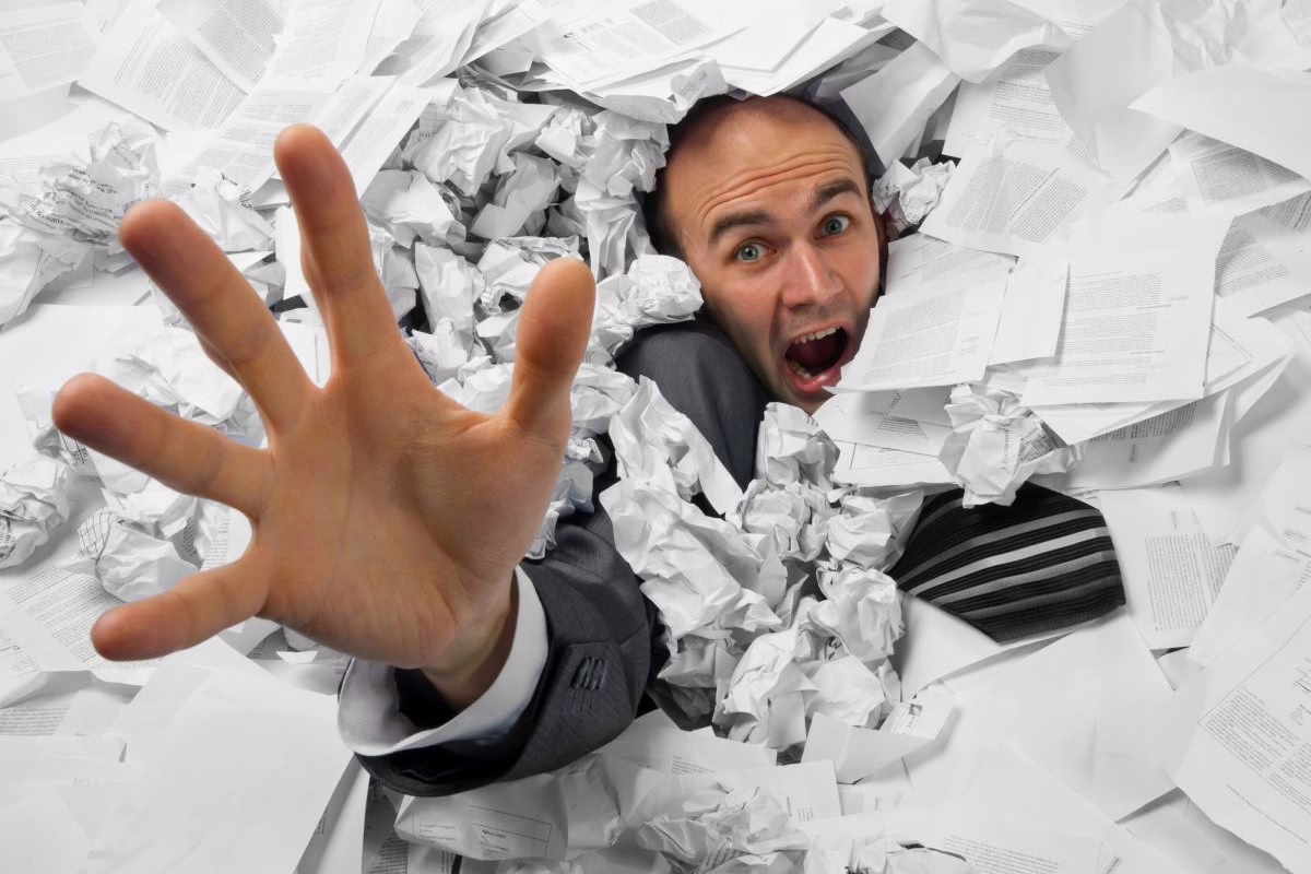 Working with a disability. Man buried in paperwork.