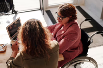 Woman in wheelchair and colleague looking at computer.