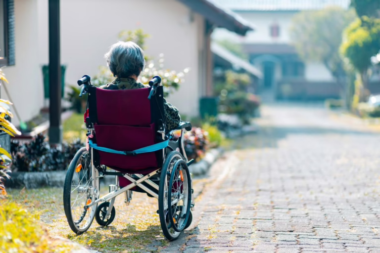 Elderly woman in wheelchair sitting outdoors.