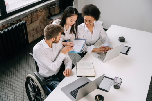 Man in a wheelchair with colleagues.