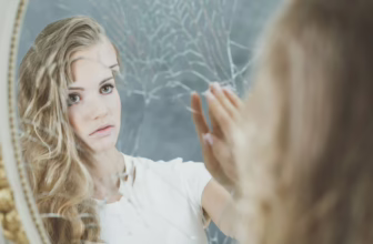 Sad woman looking in mirror.