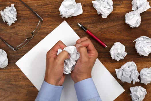Stressed writer crumpling balls of paper.