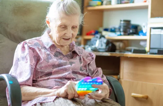 Senior woman in memory care playing with a fidget toy.