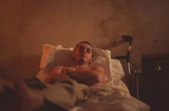 Depressed man laying in bed with crutches nearby.