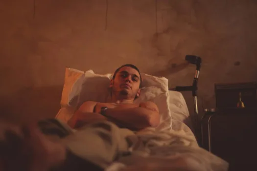 Depressed man laying in bed with crutches nearby.