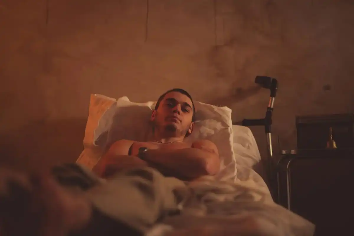 Depressed man laying in bed with crutches nearby.