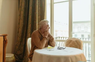 Elderly man looking out window.