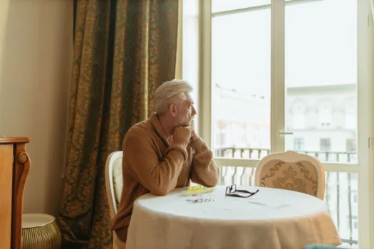 Elderly man looking out window.